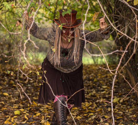 Girl hide in woods while wearing blonde and brown colored dreadlock extensions.